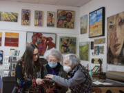 Maria Gonser, left, her mom Diana Faville and Portland artist Sidonie Caron look over historic photos of the Attic Gallery in its different locations. Fifty-one years after it opened in Portland, the family-operated Attic Gallery is preparing to close its doors in Camas.