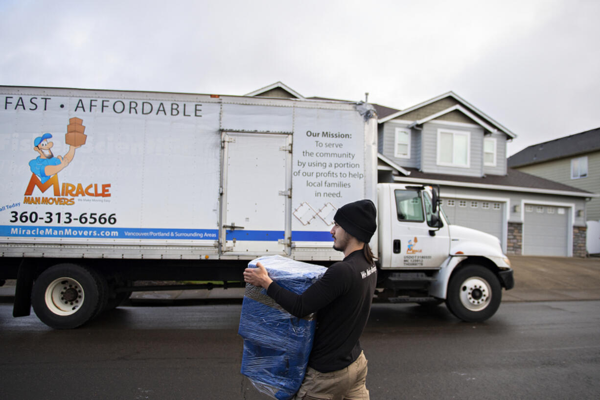 Xavier Lopez of Miracle Man Movers transports a piece of furniture from a container to his truck while moving a customer to Vancouver in March 2023. Application and other fees can make moving costly for renters.