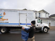 Xavier Lopez of Miracle Man Movers transports a piece of furniture from a container to his truck while moving a customer to Vancouver in March 2023. Application and other fees can make moving costly for renters.