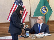 Washington Gov. Jay Inslee, seated, honored Eduardo Carrillo with a special proclamation for his work as the designated &ldquo;bill crier.&rdquo; With a booming voice, Carrillo called out each bill Inslee was about to sign so people who came to watch could make sure they were present.