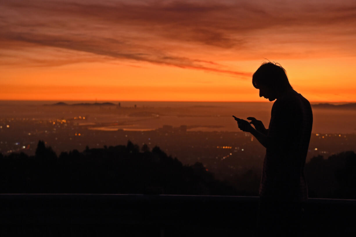 Kris Bel, of Concord, checks his smartphone from Grizzly Peak Boulevard in Oakland, California, on Saturday, Oct. 26, 2019. A 2024 bill could make California the first state to give workers the right to ignore calls, texts, emails, and other communications from work outside their normal work hours.