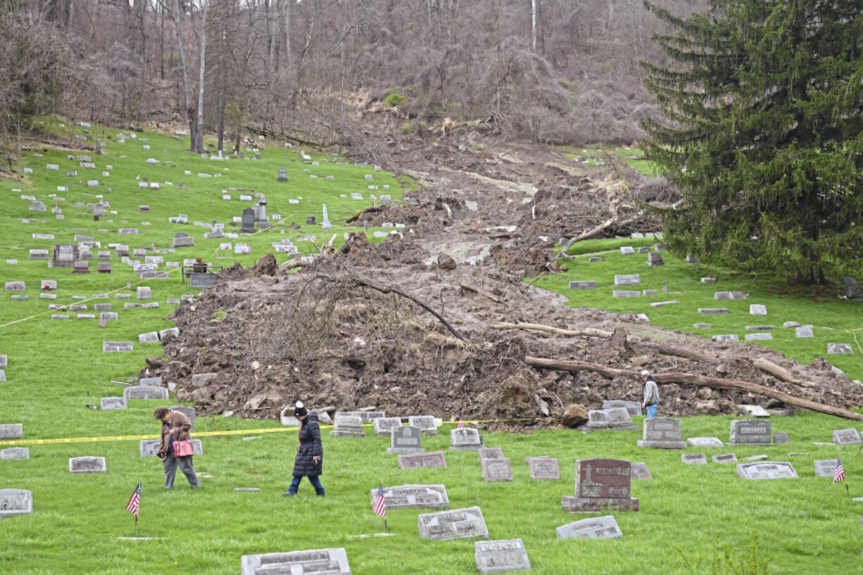 Family members check on the graves of relatives in the Wheeling Mt. Zion Cemetery Saturday, April 6, 2024, following a landslide earlier this week caused by heavy rainfall  in and around Wheeling, West Virginia.
