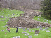 Family members check on the graves of relatives in the Wheeling Mt. Zion Cemetery Saturday, April 6, 2024, following a landslide earlier this week caused by heavy rainfall  in and around Wheeling, West Virginia.