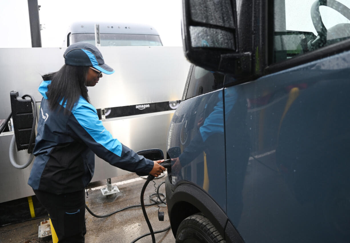 Kayla Dudley, 24, driver associate at Amazon, unplugs the electrical power cable from her new Amazon EV delivery truck, which is on Rivian&Ccedil;&fnof;&Ugrave;s truck platform, at Pontiac Amazon Fulfillment Center, April 2, 2024, in Pontiac, Michigan.