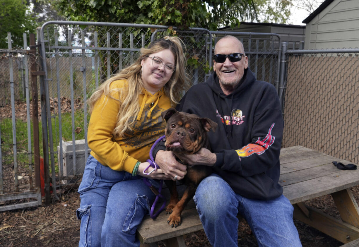 People pose with a dog they decided to adopt at Oakland Animal Services on April 4 in Oakland, Calif. The city animal shelter has seen a surge in pets surrendered by tenants who can&rsquo;t find rentals that allow pets.