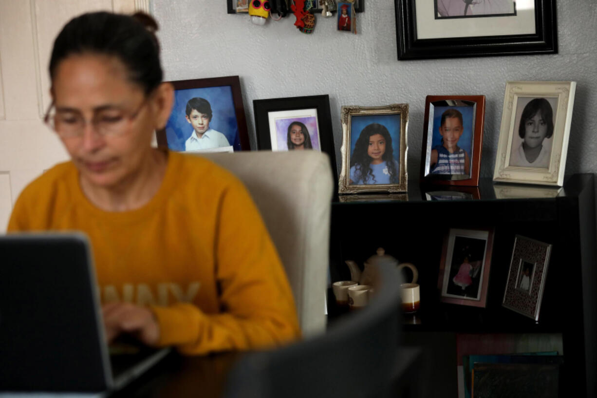 Claudia Alleman works on her computer, against a backdrop of photos of her family, in the living room of her family home in South Gate, California, on April 18, 2024. The Alleman family will be impacted when the federal internet subsidy program Affordable Connectivity Program will run out of funds next week. Thousands will be impacted in Los Angeles County when the program runs out of funds.