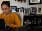 Claudia Alleman works on her computer, against a backdrop of photos of her family, in the living room of her family home in South Gate, California, on April 18, 2024. The Alleman family will be impacted when the federal internet subsidy program Affordable Connectivity Program will run out of funds next week. Thousands will be impacted in Los Angeles County when the program runs out of funds.