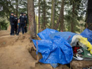 Members of the Vancouver Police Department respond to a call of a dead person suspected to have overdosed at a homeless encampment near Hazel Dell on April 4.  At top, Officer Cole Larson of the Vancouver Police Department confiscates a device for smoking fentanyl from a motorist while on patrol April 4.