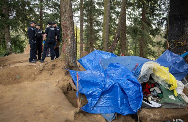 Members of the Vancouver Police Department respond to a call of a dead person suspected to have overdosed at a homeless encampment near Hazel Dell on April 4.  At top, Officer Cole Larson of the Vancouver Police Department confiscates a device for smoking fentanyl from a motorist while on patrol April 4.