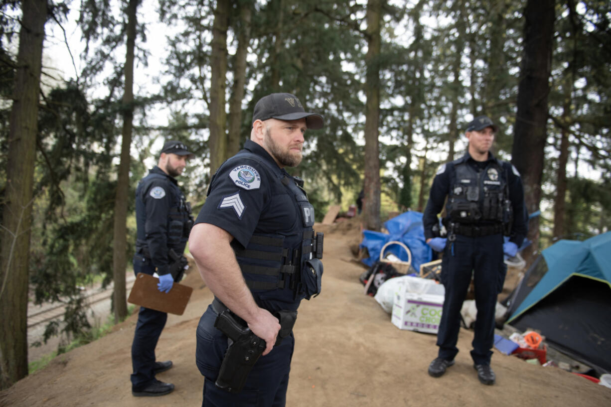 Vancouver police Patrol Sgt. Zachary Ripp, center, works with colleagues while responding to a call of a dead person at a homeless encampment Thursday afternoon near Hazel Dell. Five officers responded to the call, which combined with another call at the same time, tied up all the officers working on the west side of the city.