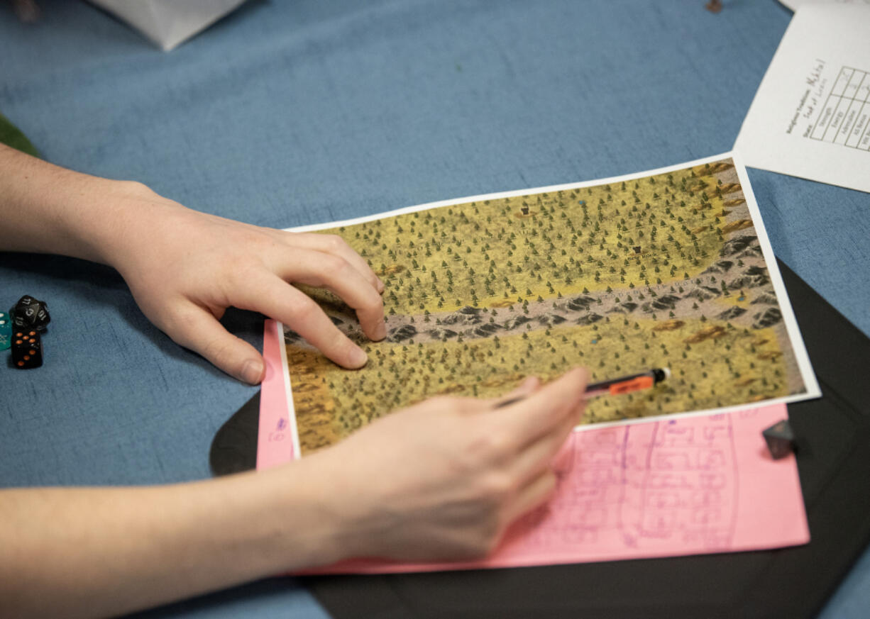 Travis Haslem of Battle Ground shows players a printout of the land they're traveling through while playing a Dungeons & Dragons spinoff at Dice Age Games in Vancouver.