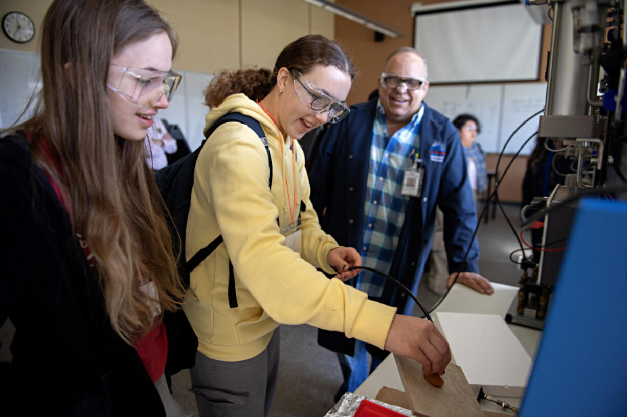 Students Bella Bir, 16, from left, and Garance Herve-Mignucci, 15, use vacuum technology to pick up different items during a tour of the Clark College Columbia Tech Center campus hydraulic and pneumatics systems lab.
