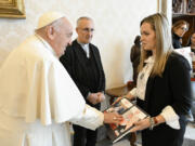 Pope Francis touches a photograph of a child as he meets with Ashley Waxman Bakshi, right, and other relatives of Israeli hostages being held by Hamas, at the Vatican, Monday, April 8, 2024. Israel sent troops to Khan Younis in December, part of its blistering ground offensive that came in response to a Hamas-led attack on Oct. 7 into southern Israel. Israeli authorities say 1,200 people, mostly civilians, were killed and roughly 250 people taken hostage.