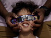 FILE - Viewers use special glasses to watch from San Antonio, as the moon moves in front of the sun during an annular solar eclipse, or ring of fire, Oct. 14, 2023. The total solar eclipse on April 8, 2024 may be weeks away but businesses are ready for the celestial event with oodles of special eclipse glasses for sale, along with T-shirts and other souvenirs.