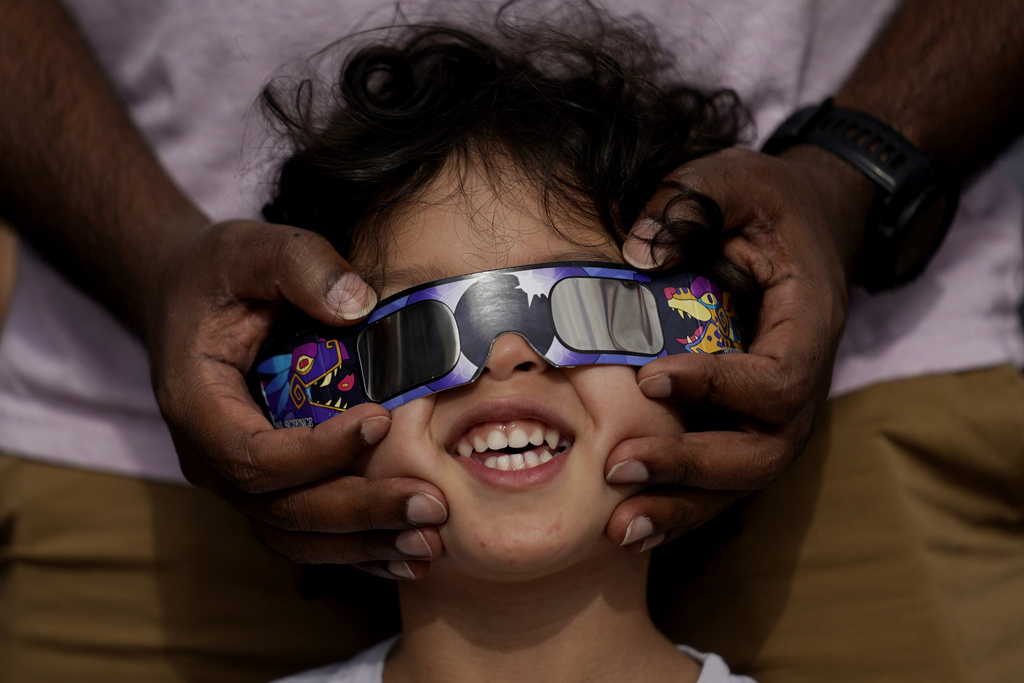 FILE - Viewers use special glasses to watch from San Antonio, as the moon moves in front of the sun during an annular solar eclipse, or ring of fire, Oct. 14, 2023. The total solar eclipse on April 8, 2024 may be weeks away but businesses are ready for the celestial event with oodles of special eclipse glasses for sale, along with T-shirts and other souvenirs.