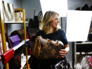 Deborah Mayer holds one of the luxury handbags she sells on TikTok, Wednesday, March 21, 2024, in Freehold, N.J. Mayer has sold new and pre-owned handbags and other designer goods out of her New Jersey home for 16 years. Early last year, TikTok recruited her business for the live component of TikTok Shop. (AP Photo/Noah K.