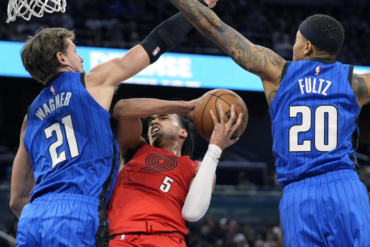 Orlando Magic center Moritz Wagner (21) fouls Portland Trail Blazers guard Dalano Banton (5) as he goes up for a shot past guard Markelle Fultz (20) during the first half of an NBA basketball game, Monday, April 1, 2024, in Orlando, Fla.