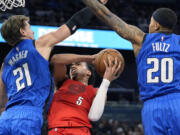 Orlando Magic center Moritz Wagner (21) fouls Portland Trail Blazers guard Dalano Banton (5) as he goes up for a shot past guard Markelle Fultz (20) during the first half of an NBA basketball game, Monday, April 1, 2024, in Orlando, Fla.