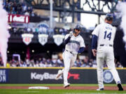 Seattle Mariners' Dominic Canzone celebrates with third base coach Manny Acta (14) after hitting a three-run home run against the Cleveland Guardians during the second inning of a baseball game Monday, April 1, 2024, in Seattle.