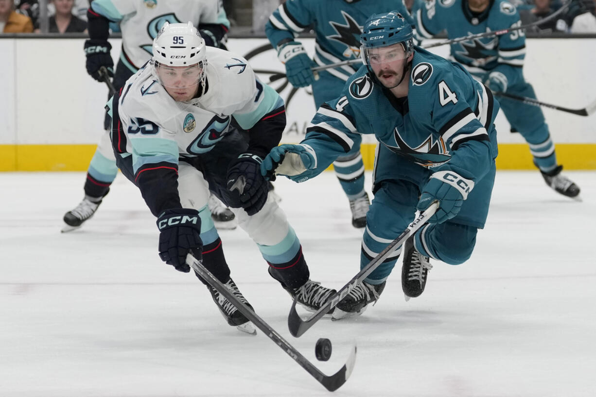 Seattle Kraken left wing Andre Burakovsky (95) reaches for the puck against San Jose Sharks defenseman Kyle Burroughs (4) during the second period of an NHL hockey game in San Jose, Calif., Monday, April 1, 2024.
