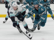 Seattle Kraken left wing Andre Burakovsky (95) reaches for the puck against San Jose Sharks defenseman Kyle Burroughs (4) during the second period of an NHL hockey game in San Jose, Calif., Monday, April 1, 2024.