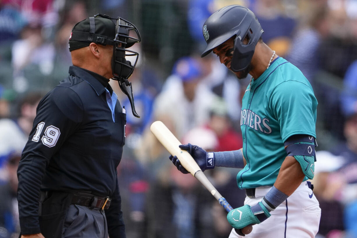 Seattle Mariners' Julio Rodríguez reacts to being called out on strikes by home plate umpire Vic Carapazza, left, against the Cleveland Guardians during the third inning of a baseball game Wednesday, April 3, 2024, in Seattle.