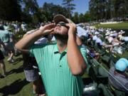 A patron looks up at the sun during an solar eclipse during a practice round in preparation for the Masters golf tournament at Augusta National Golf Club Monday, April 8, 2024, in Augusta, Ga.