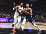 Golden State Warriors guard Stephen Curry, right, drives to the basket against Portland Trail Blazers forward Justin Minaya, left, during the first half of an NBA basketball game in Portland, Ore., Thursday, April 11, 2024.