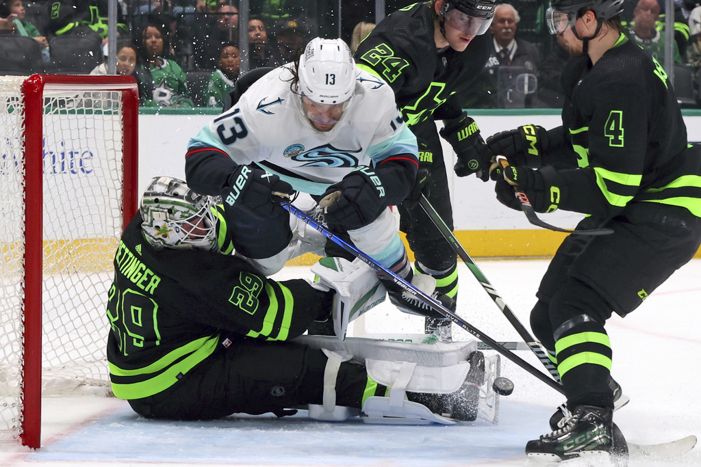 Dallas Stars goaltender Jake Oettinger (29) gets slammed into by Seattle Kraken left wing Brandon Tanev (13) as he shoots in the second period of an NHL hockey game on Saturday, April 13, 2024, in Dallas. (AP Photo/Richard W.