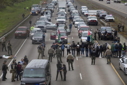 Anti- Israel protesters are detained as they block the southbound lane of Interstate 5 under the Harlow overpass between Eugene, Ore., and Springfield on Monday, April 15, 2024.
