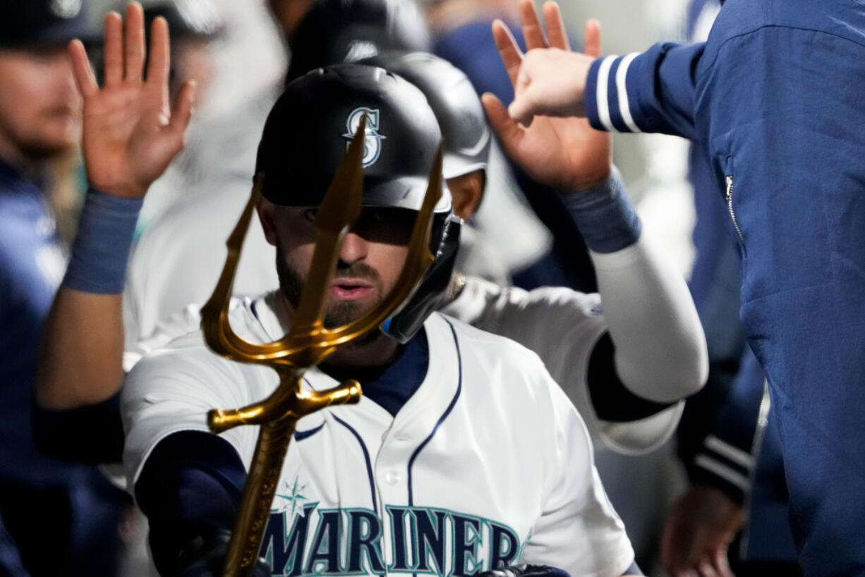 Seattle Mariners' Mitch Haniger points a trident in the dugout after hitting a two-run home run against the Cincinnati Reds during the third inning of a baseball game Monday, April 15, 2024, in Seattle.