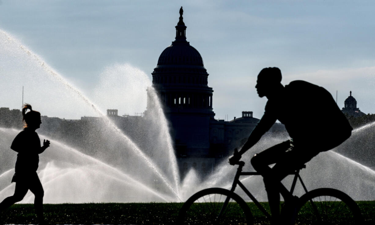 FILE - The Capitol is seen as water sprinklers soak the National Mall on a hot summer morning in Washington, July 15, 2022. A new poll finds that most Americans share many core values on what it means to be an American despite the country&rsquo;s deep political polarization. The poll from The Associated Press-NORC Center for Public Affairs Research found that about 9 in 10 U.S. adults say the right to vote, the right to equal protection under the law and the right to privacy are important or very important to the U.S.&rsquo;s identity as a nation.(AP Photo/J.