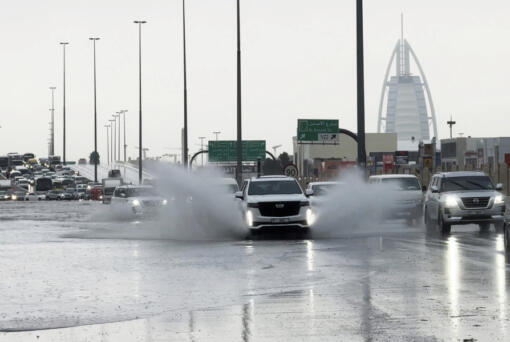 An SUV splashes through standing water on a road with the Burj Al Arab luxury hotel seen in the background in Dubai, United Arab Emirates, Tuesday, April 16, 2024. Heavy rains lashed the United Arab Emirates on Tuesday, flooding out portions of major highways and leaving vehicles abandoned on roadways across Dubai. Meanwhile, the death toll in separate heavy flooding in neighboring Oman rose to 18 with others still missing as the sultanate prepared for the storm.