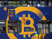 FILE - An advertisement for the cryptocurrency Bitcoin displayed on a tram, May 12, 2021, in Hong Kong. Sometime in the next few days or even hours, the &ldquo;miners&rdquo; who chisel bitcoins out of complex mathematics are going to take a 50% pay cut &mdash; effectively slicing new emissions of the world&rsquo;s largest cryptocurrency in an event called bitcoin halving.