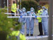 Forensics officers gesture near the scene of an attack in Hainault, north east London, Tuesday April 30, 2024. A man wielding a sword attacked members of the public and police officers in a east London suburb, killing a 13-year-old boy and injuring four others, authorities said Tuesday. The man was arrested at the scene, police said. Chief Supt.