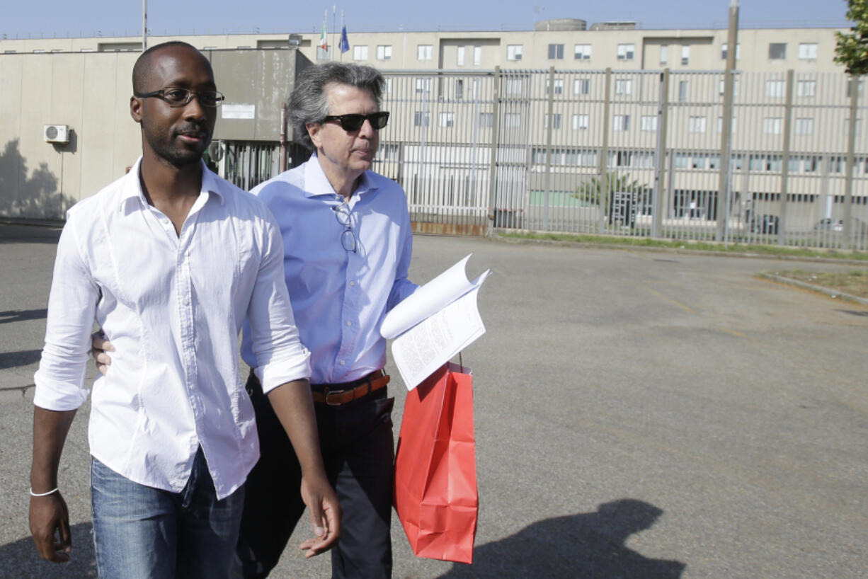 FILE - Rudy Guede, left, leaves the penitentiary for a temporary release of thirty-six hours, in Viterbo, Italy, on June 25, 2016. Guede, the only person convicted in the 2007 murder of British student Meredith Kercher has been freed after serving most of his 16-year prison sentence. Amanda Knox faces yet another trial for slander in a case that could remove the last remaining guilty verdict against her nine years after Italy&rsquo;s highest court definitively threw out her conviction for the murder of her 21-year-old British roommate, Meredith Kercher.