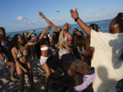 FILE - A group of students from Ole Miss, the University of Mississippi, dance and sing as they enjoy spring break on South Beach, Friday, March 15, 2024, in Miami Beach, Fla. Another month, another heat record for the planet. Earth just had its warmest March ever recorded, the 10th month in a row to set such a record, according to the European Union climate agency Copernicus.