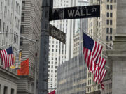 American flags hang from the front the New York Stock Exchange, right, on Thursday, April 11, 2024 in New York. Shares in Europe and Asia are mostly lower after U.S. stocks fell following another release of hotter than expected inflation data.