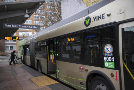 A cyclist boards a C-Tran Vine bus at the Turtle Place Transit Center in downtown Vancouver in 2021.