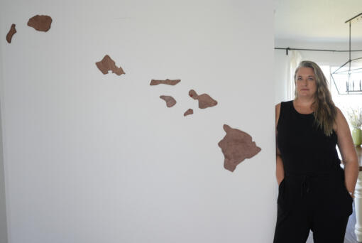 Amy Chadwick, stands by map of Hawaii at her current home Monday, April 8, 2024, in Satellite Beach, Fla. Chadwick, a victim of the fires in Hawaii moved to Florida where she could stretch her homeowners insurance dollars while she waits for her lot to be cleared and for permission to rebuild.