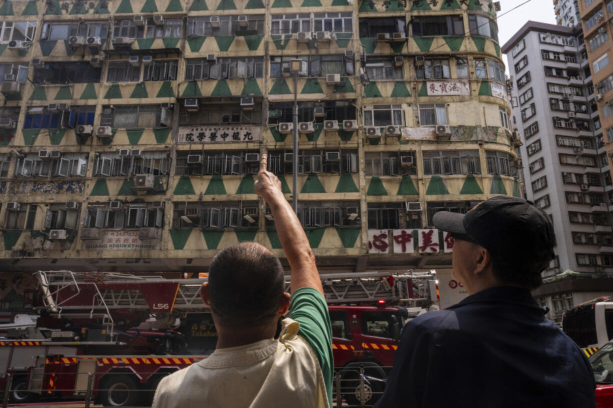 Onlookers stand near a building called New Lucky House where a fire started in Hong Kong, Wednesday, April 10, 2024.