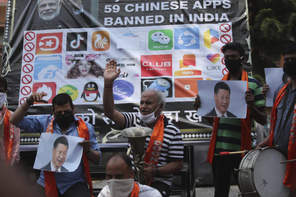 FILE- Activists of Jammu and Kashmir Dogra Front shout slogans against Chinese President Xi Jinping next to a banner showing the logos of TikTok and other Chinese apps banned in India during a protest in Jammu, India,  July 1, 2020.