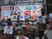 FILE- Activists of Jammu and Kashmir Dogra Front shout slogans against Chinese President Xi Jinping next to a banner showing the logos of TikTok and other Chinese apps banned in India during a protest in Jammu, India,  July 1, 2020.
