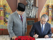 Indonesian President-elect and current Defense Minister Prabowo Subianto, left, stands next to Chinese Foreign Minister Wang Yi as Wang signs a guest book in Jakarta, Indonesia, Thursday, April 18, 2024.