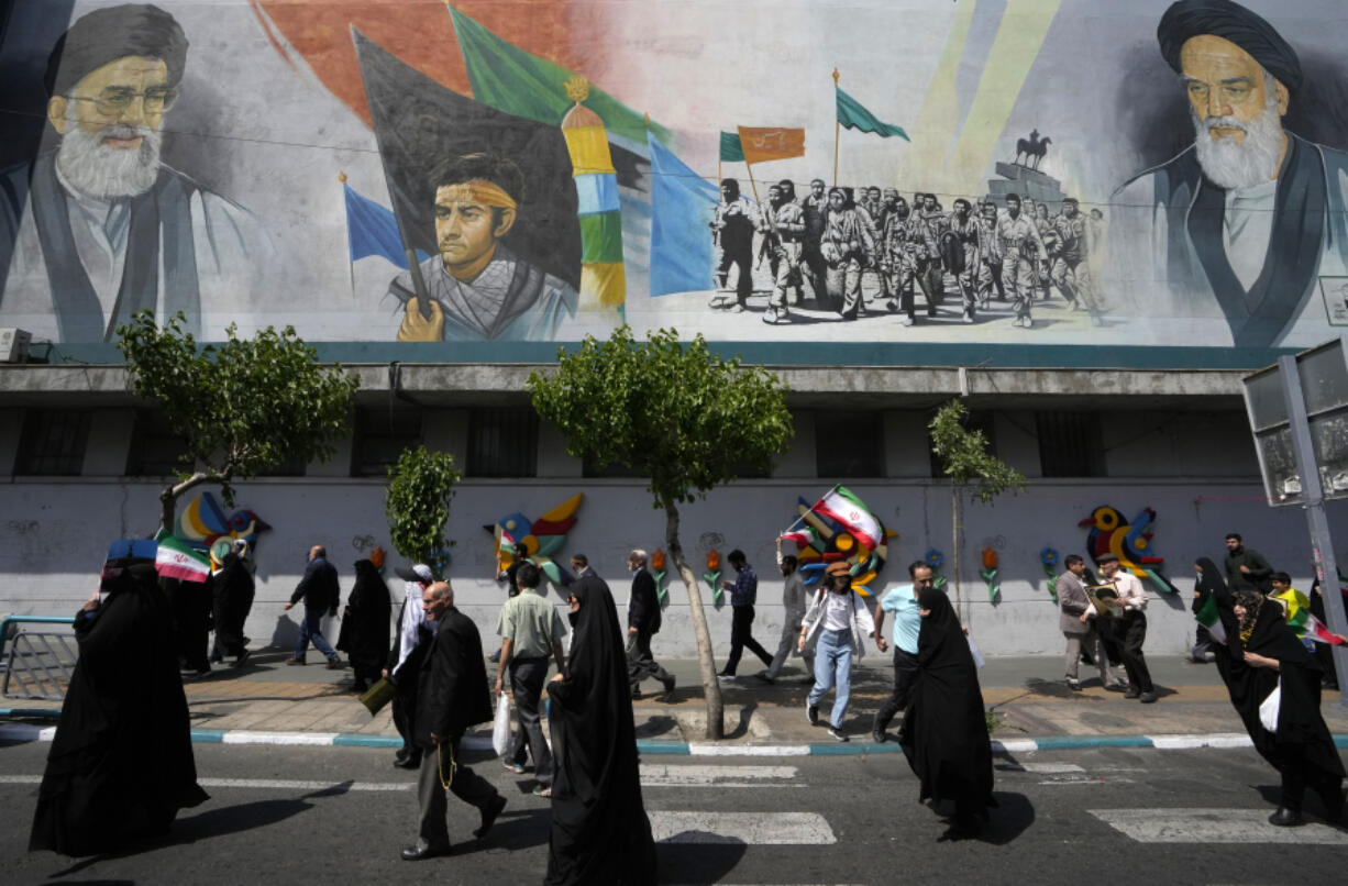 Iranian worshippers walk past a mural showing the late revolutionary founder Ayatollah Khomeini, right, Supreme Leader Ayatollah Ali Khamenei, left, and Basij paramilitary force, in an anti-Israeli gathering after their Friday prayer in Tehran, Iran, Friday, April 19, 2024. An apparent Israeli drone attack on Iran saw troops fire air defenses at a major air base and a nuclear site early Friday morning near the central city of Isfahan, an assault coming in retaliation for Tehran&rsquo;s unprecedented drone-and-missile assault on the country.