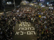 People gather next to a sign displayed on the street that reads in Hebrew &ldquo;Rafah can wait, they cannot&rdquo;, in reference of a possible Israeli offensive on the Rafah, city in southern Gaza Strip, and calling for the release of the Israeli hostages held by the Hamas militant group, during a protest in Tel Aviv, Monday, April 29, 2024.