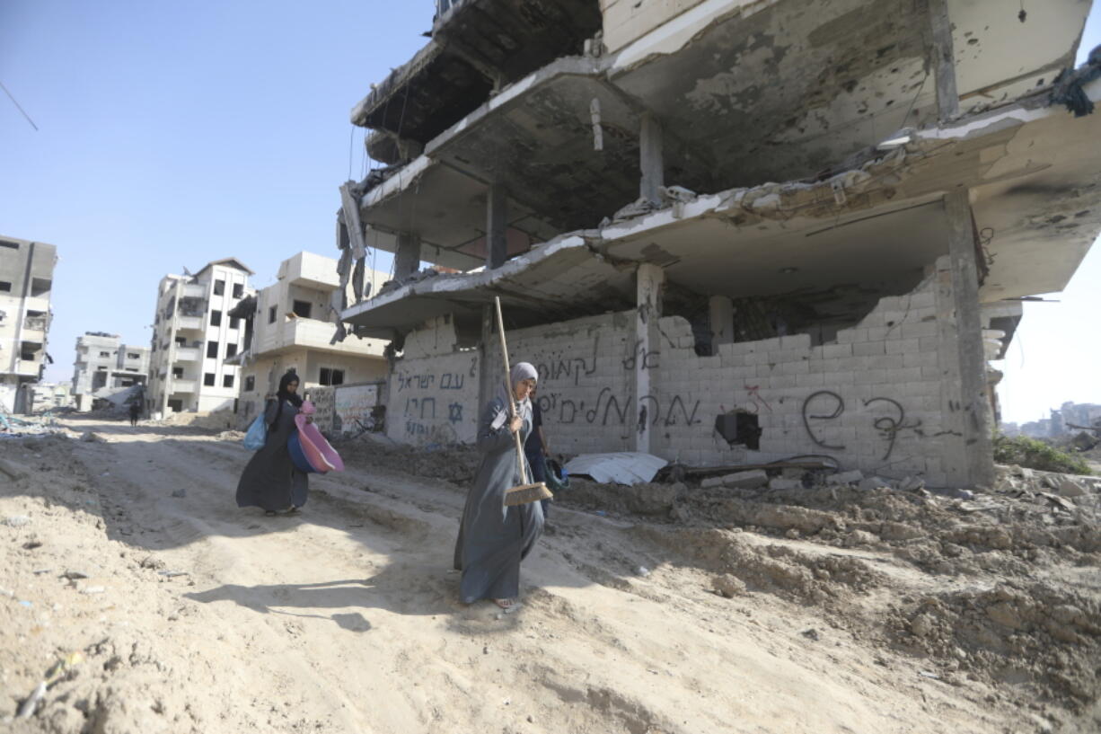 Palestinians walk through the destruction left by the Israeli air and ground offensive after they withdrew from Khan Younis, Gaza Strip, Sunday, April 7, 2024.