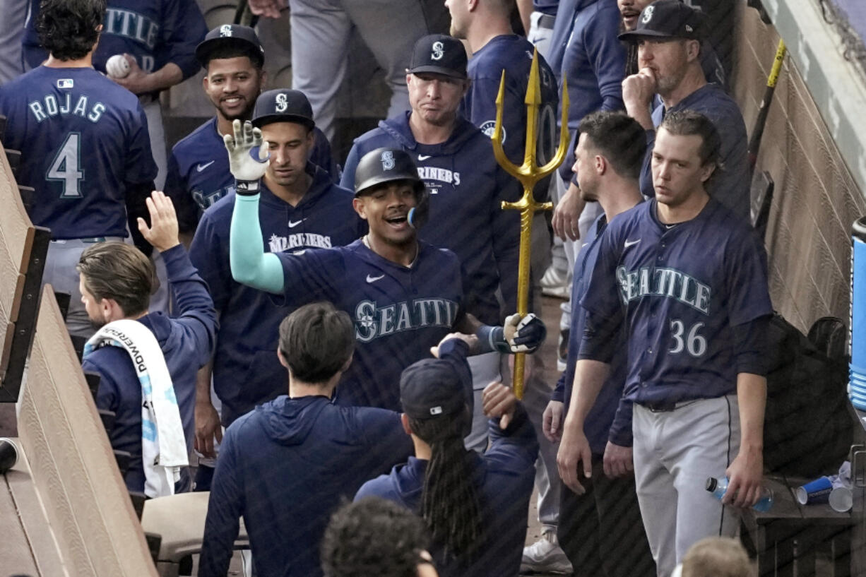 Seattle Mariners&#039; Julio Rodriguez holds a trident in the dugout after hitting a two-run home run against the Texas Rangers during the third inning of a baseball game in Arlington, Texas, Tuesday, April 23, 2024.