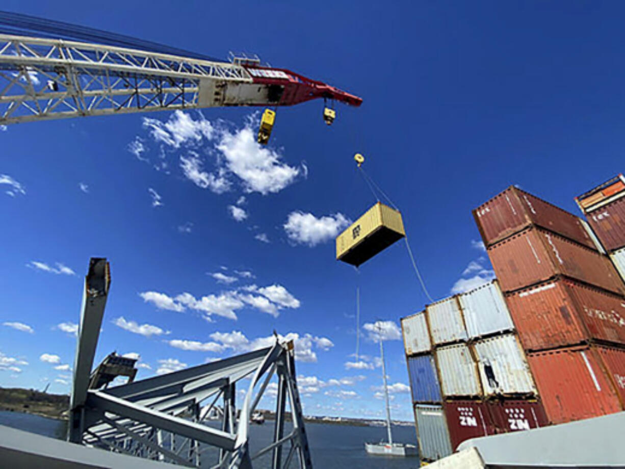In this photo provided by the Key Bridge Response 2024 Unified Command, response crews begin removing shipping containers from the deck of the cargo ship Dali using a floating crane barge at the site of the Francis Scott Key Bridge, Sunday, April 7, 2024, in Baltimore.
