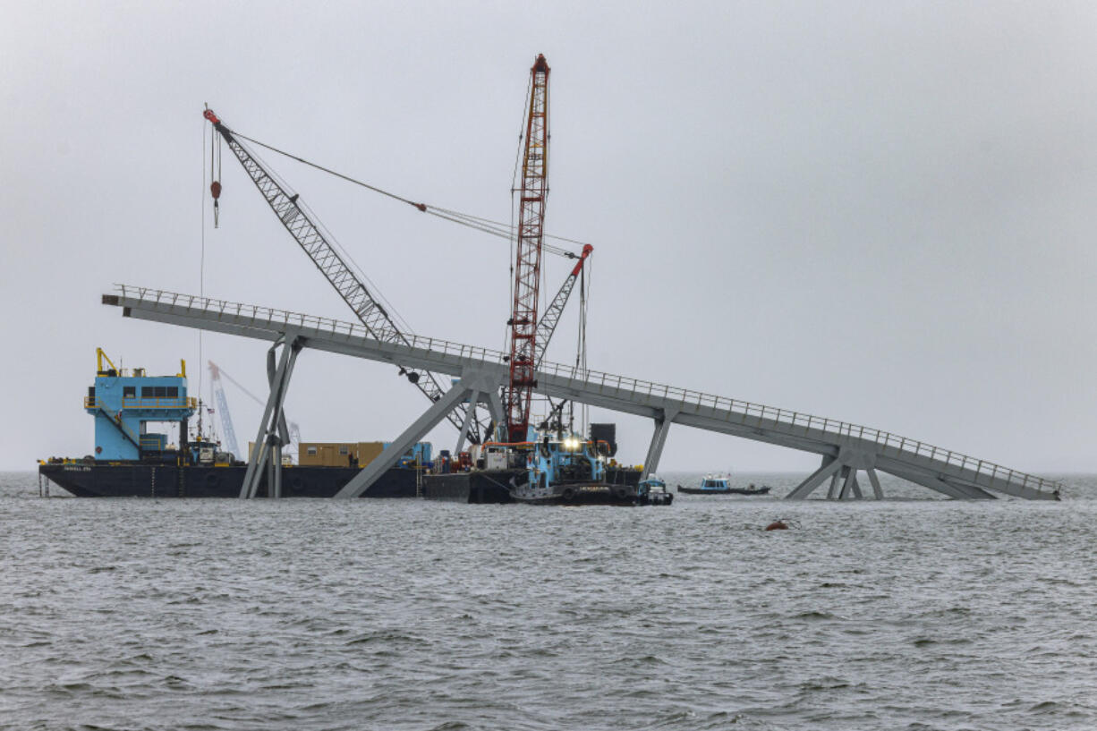 Cranes continue salvage work as wreckage of the Francis Scott Key Bridge rests on the container ship Dali, Wednesday, April 3, 2024, in Baltimore.